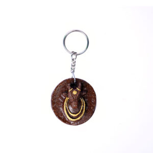 Handcrafted round Gomaya keychain with cow face design and steel ring.
